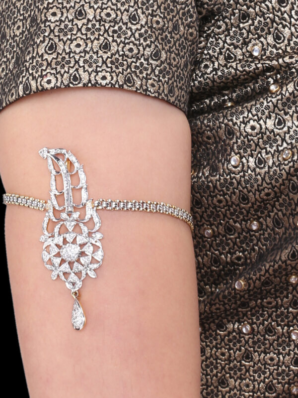 Close-up of an ornate diamond bracelet draped on the upper arm against a patterned fabric sleeve, highlighting shine and design symmetry.