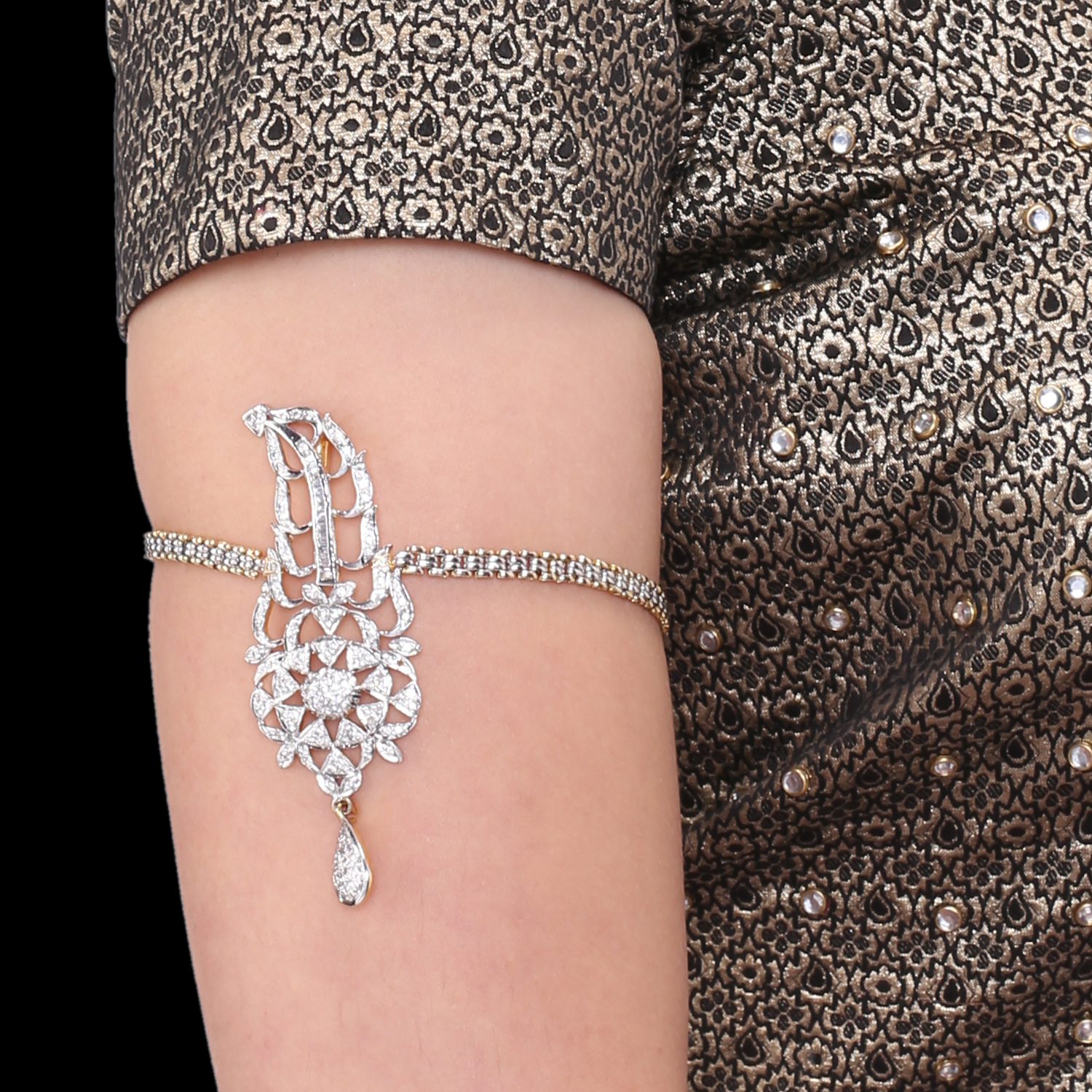 Close-up of an ornate diamond bracelet draped on the upper arm against a patterned fabric sleeve, highlighting shine and design symmetry.