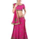 Woman in a bright pink traditional Indian lehenga with gold embroidery, posing with hand on hip and a matching dupatta over her shoulder.
