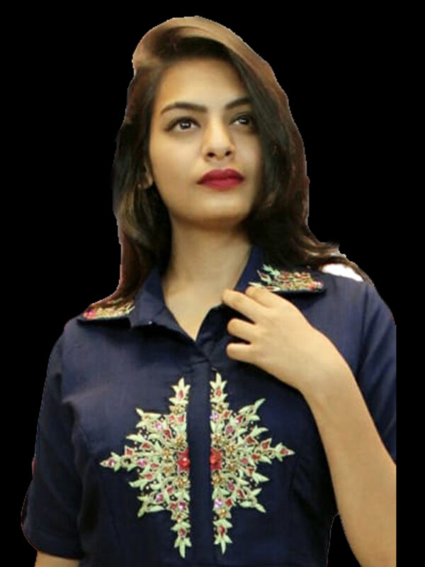 Portrait of a young woman with dark hair, wearing a navy embroidered shirt, looking upward.